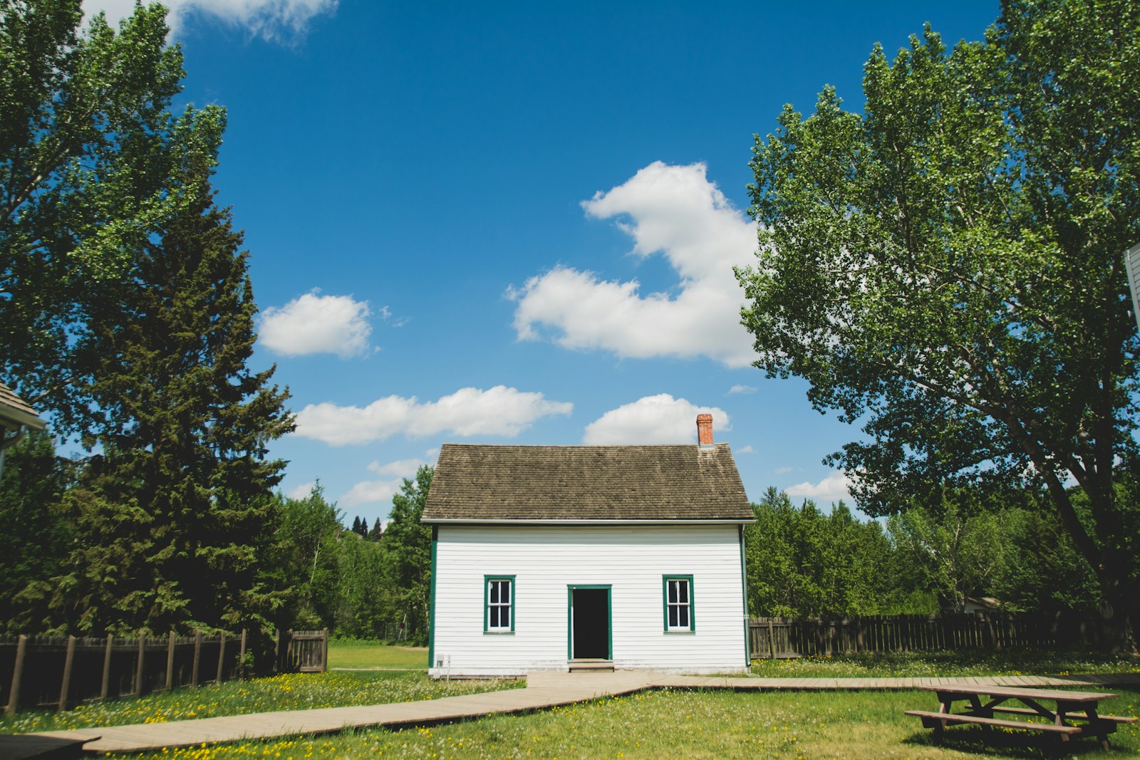white wooden house between trees symbolizing filing a homeowners insurance claim
